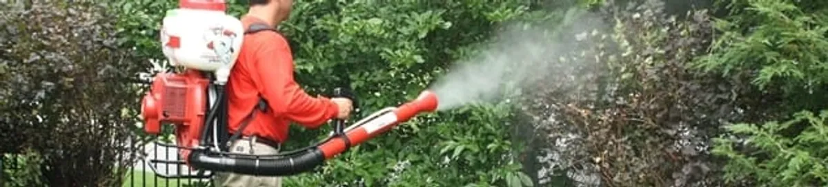 Mosquito control technician fogging shrubs and landscaping for mosquito treatment in Minneapolis, MN