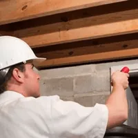 Termite inspection technician checking a basement wall and framing for termite activity in Minneapolis, MN